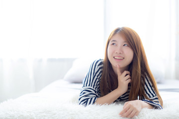 Beautiful portrait young asian woman lying and smile while wakeup with sunrise at morning, girl thinking idea something lifestyle and relax concept.