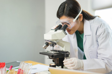 Female medical Doctor or research scientist looking through a microscope in a laboratory.science experiments,laboratory glassware containing chemical liquid for researching biology chemistry samples