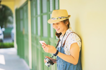 Asian woman walking and using a smart phone in the street ,Modern people city lifestyle. Young girl using phone app and earphones to listen to music or play video games online. enjoying  lifestyle