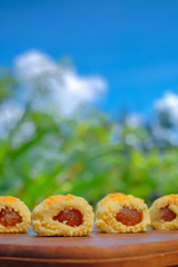 Closeup of a pineapple tart outdoors in a garden with blue sky as background