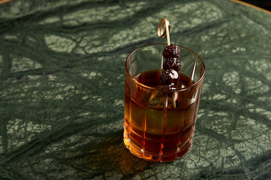 Artichoke Negroni cocktail on bar table. Tart, man's cocktail with Gin alcohol , Rosso, Cynar, close-up