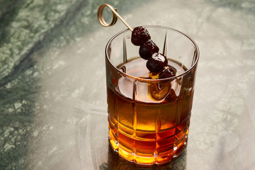 Artichoke Negroni cocktail on bar table. Tart, man's cocktail with Gin alcohol , Rosso, Cynar, close-up