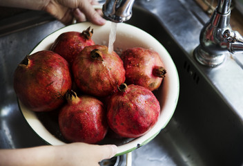 A person washing pomegranate under running water food photography idea