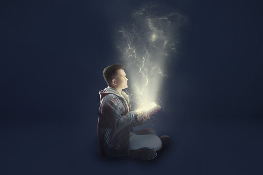A school boy wearing a jacket holding and reading a magical book with mystical light coming out. Ideas from reading. Depicting education.