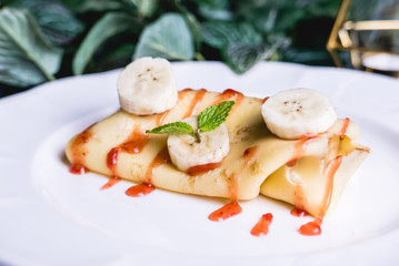 sweet crepe filled with banana set on table.