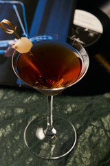 Vinyl Manhattan cocktail on bar table. Freshness Alcoholic beverage drink with whiskey, rosso, rosehip bitter, fernet branca menta ingredients, close-up