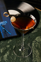 Vinyl Manhattan cocktail on bar table. Freshness Alcoholic beverage drink with whiskey, rosso, rosehip bitter, fernet branca menta ingredients, close-up