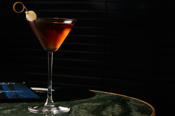 Vinyl Manhattan cocktail on bar table. Freshness Alcoholic beverage drink with whiskey, rosso, rosehip bitter, fernet branca menta ingredients, close-up