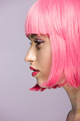 side view of attractive woman with pink hair and glitter on face isolated on violet