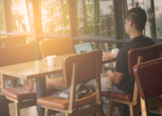 blurred image of man using laptop at coffee shop.