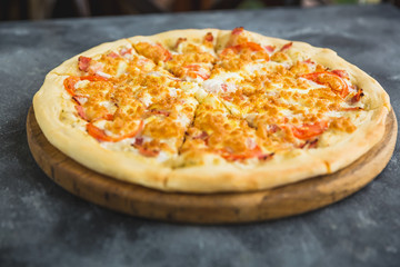 Delicious pizza with bacon, cheese, tomato on dark background.