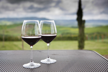 two glasses of red wine against beautiful landscape in Tuscany