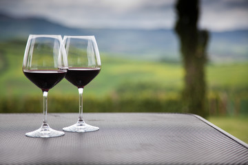 two glasses of red wine against beautiful landscape in Tuscany