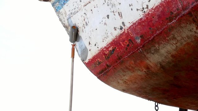 Worker covers metal with a primer paint of old rusty ship at shipyard in port. Process of repair and reconstruction of sea vessel.Technology of manual painting boats. Industry of water transport.
