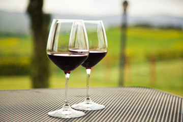 two glasses of red wine against beautiful landscape in Tuscany