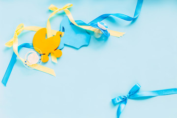 baby accessories on blue background, like soother, nipple, wooden clothes, wooden small baby stoller