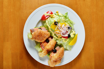  Smoked salmon croissants with salad on the plate