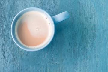 Milk coffee in a blue cup on pastel blue wooden floor