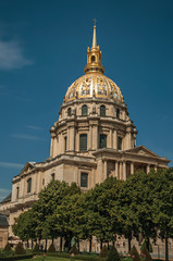 Obraz premium Trees in the gardens of Les Invalides Palace with the golden dome in a sunny day at Paris. Known as the “City of Light”, is one of the most impressive world’s cultural center. Northern France.