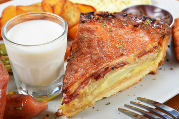 A slice of bacon and cheese quiche lorraine on a white plate          