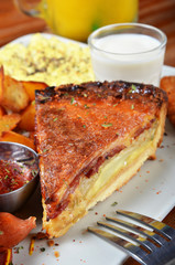 A slice of bacon and cheese quiche lorraine on a white plate          