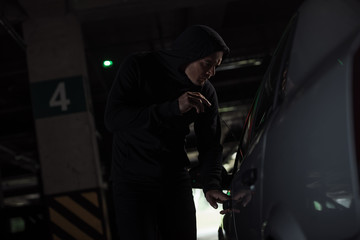 side view of focused male thief intruding car by picklock