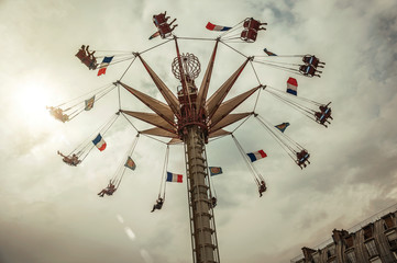 People enjoying an aerial chair ride at an amusement park on cloudy day in Paris. Known as one of the most impressive world’s cultural center. Northern France.