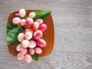 Carissa carandas or karonda are white and red with green leaves in wooden plates. On the old wood table It is a small fruit and has medicinal properties. Vitamin C is high when cooked to sour taste.
