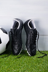 soccer ball, boots, lying on the grass, on a gray background