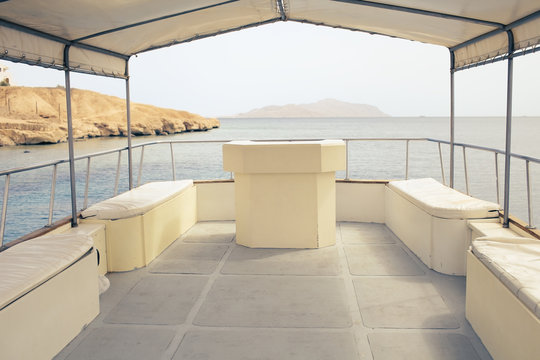 Deck Of A Pleasure Boat With White Seats And Tarpaulin Canopy