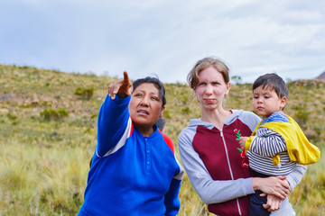 Naklejka premium Young caucasian woman with her little son asking the way to the native american woman in the countryside.