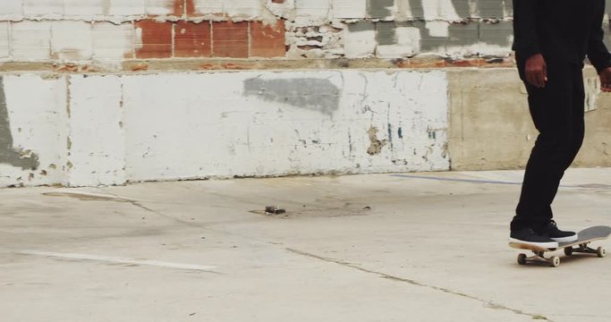 Slow motion close up of unrecognizable man skateboarding doing extreme flip trick in urban environment