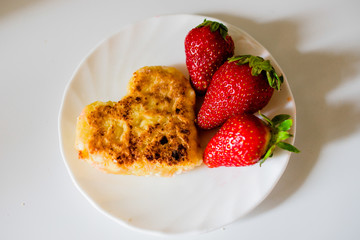 Fried cheesecakes with strawberries on a white plate