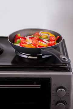 vegetables in a frying pan are cooked on modern electric stove. kitchen equipment