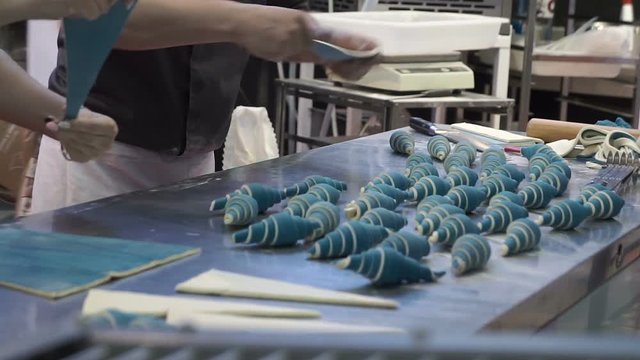 A bakers turns beautiful croissants before baking.