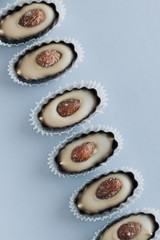 Row of delicious praline sweets with almonds on blue background