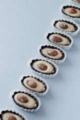 Row of delicious praline sweets with almonds on blue background