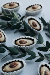 Composition of delicious praline sweets with almonds and green twigs on blue background