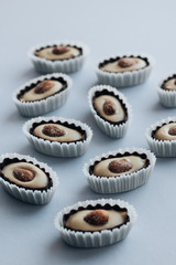 Row of delicious praline sweets with almonds on blue background