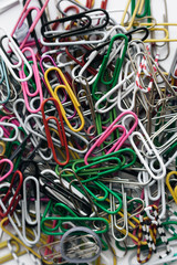 Pile of colorful paper clips on white background, flat lay