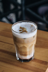 Glass of delicious cappuccino coffee on wooden table