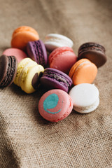 Composition of delicious colorful macaroons on sackcloth, sweet dessert
