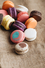 Composition of delicious colorful macaroons on sackcloth, sweet dessert