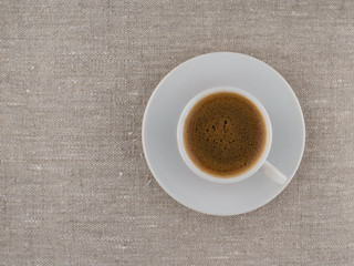 Coffee with foam in a white cup on a natural background. View from above.