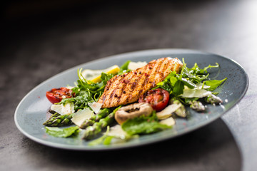 Grilled chicken breast asparagus arugula mushrooms tomatoes lemon and parmesan cheese.