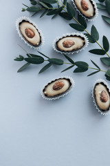 Composition of delicious praline sweets with almonds and green twigs on blue background