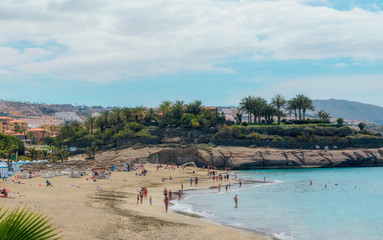 Fototapeta na wymiar People enjoying the sun at El Duque beach with warm turquoise water and gold sand in Costa Adeje, Tenerife, Canary islands, Spain