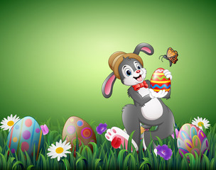 Happy Easter bunny holding Easter eggs in a field