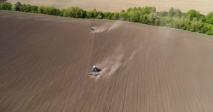 Aerial view of agricultural tractors cultivating field.
