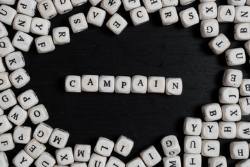 Word ICAMPAIN on wooden cubes on a black wooden table